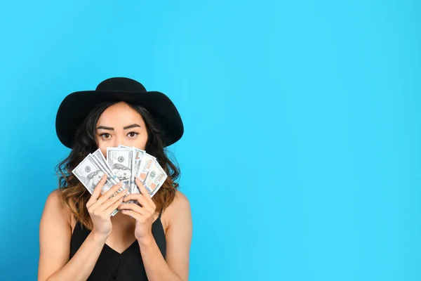 Asian woman with money on color background