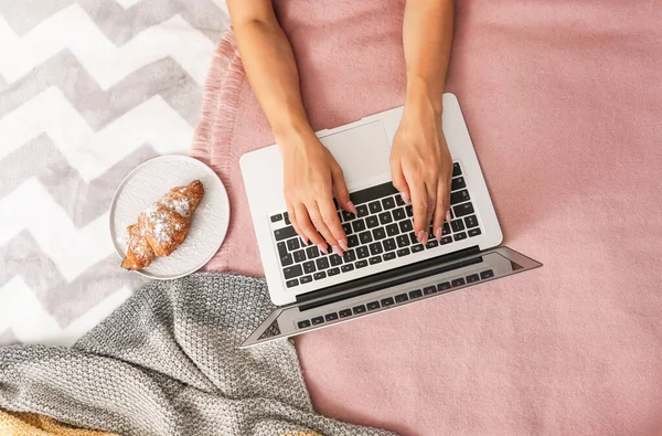 Młoda kobieta pracuje na laptopie w sypialni — Zdjęcie stockowe
