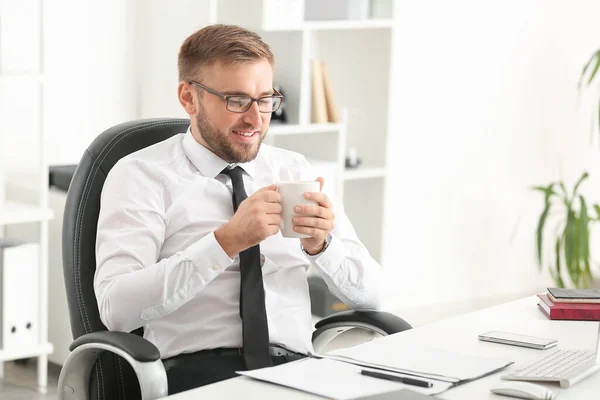 Pohledný podnikatel pití kávy v kanceláři — Stock fotografie