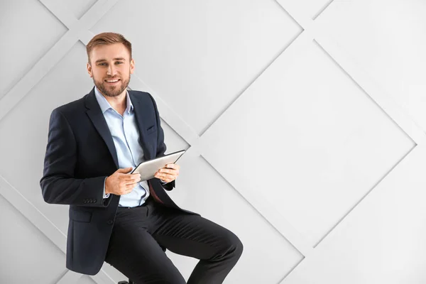 Retrato de empresário bonito com computador tablet no fundo claro — Fotografia de Stock