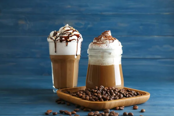 Glasses of tasty frappe coffee with beans on table — Stock Photo, Image