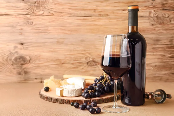 Стекло и бутылка вкусного вина с закусками на столе — стоковое фото