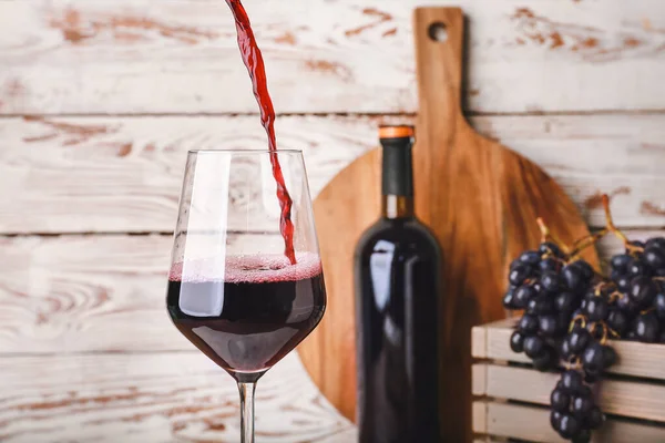 Наливание вкусного вина в бокал на деревянном фоне — стоковое фото