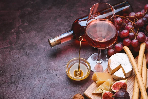 Copo e garrafa de vinho saboroso com lanches no fundo de cor — Fotografia de Stock