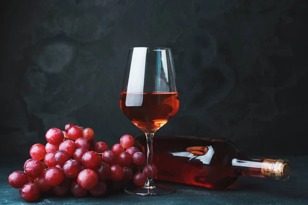 Bicchiere e bottiglia di vino gustoso su sfondo scuro — Foto Stock