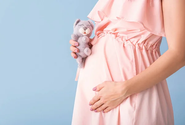 Bella giovane donna incinta con giocattolo su sfondo di colore, primo piano — Foto Stock