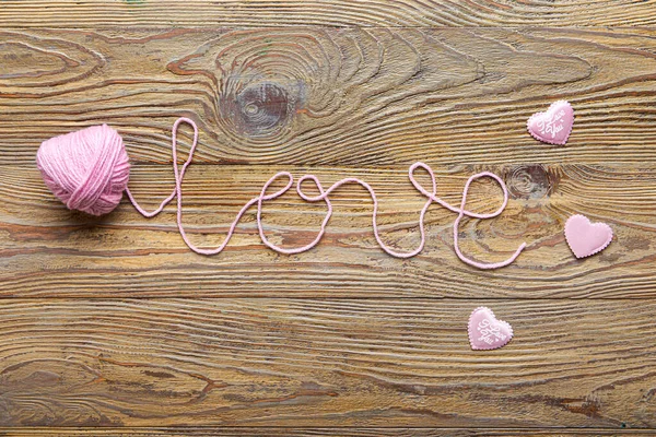 Word LOVE made of knitted yarn on wooden background