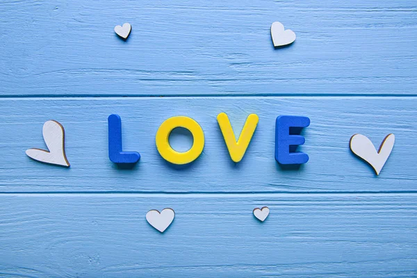 Word LOVE composed from letters and hearts on wooden background