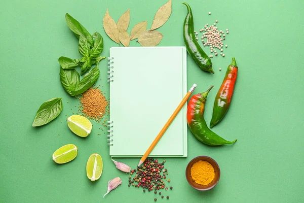 Empty notebook with different spices on color background — Stock Photo, Image