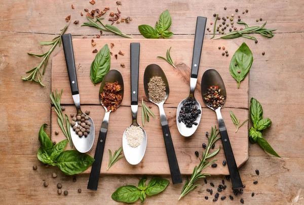 Löffel mit verschiedenen Gewürzen auf Holzgrund — Stockfoto