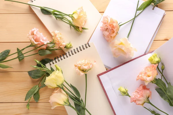 Красивые цветы из эустомы с тетрадками на деревянном фоне — стоковое фото