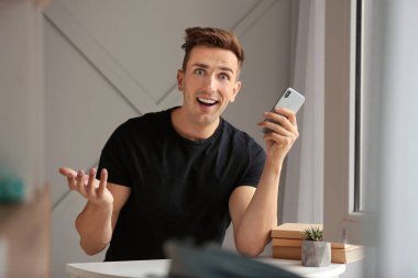 Evde cep telefonu olan mutlu bir genç adam.