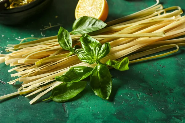 Dry pasta with basil on color background — Stock Photo, Image