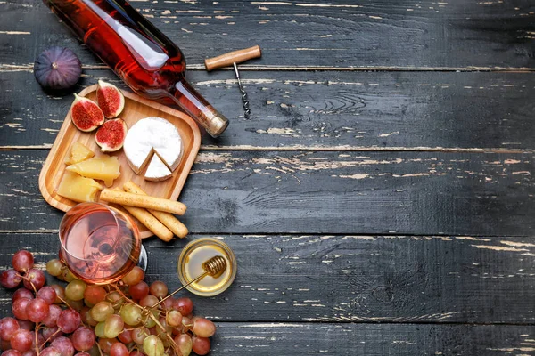 Copo e garrafa de vinho saboroso com lanches na mesa de madeira — Fotografia de Stock