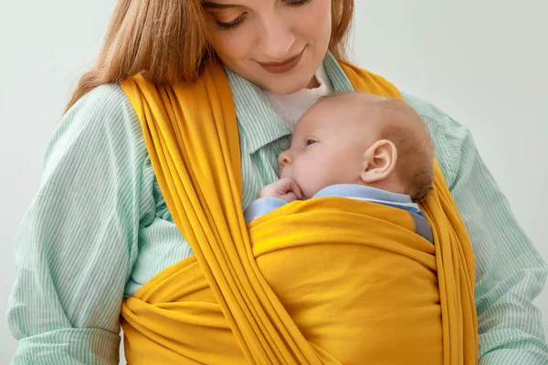 Young mother with little baby in sling on white background, closeup — Stock Photo, Image