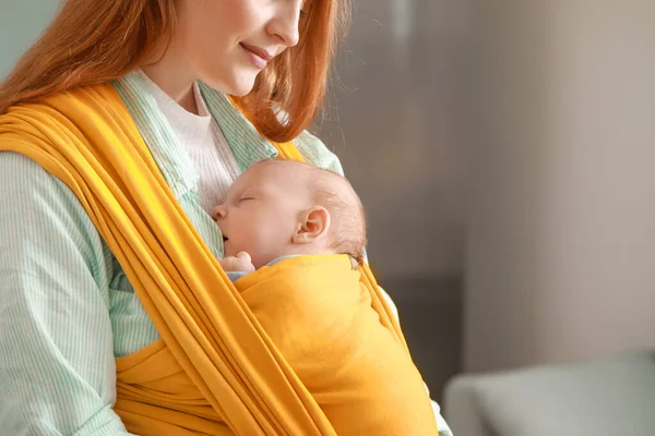 Young mother with little baby in sling at home — Stock Photo, Image