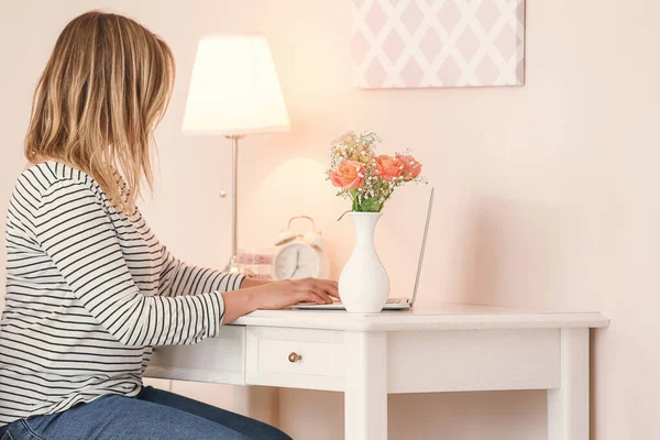 Vrouw aan tafel met mooi boeket in de kamer — Stockfoto