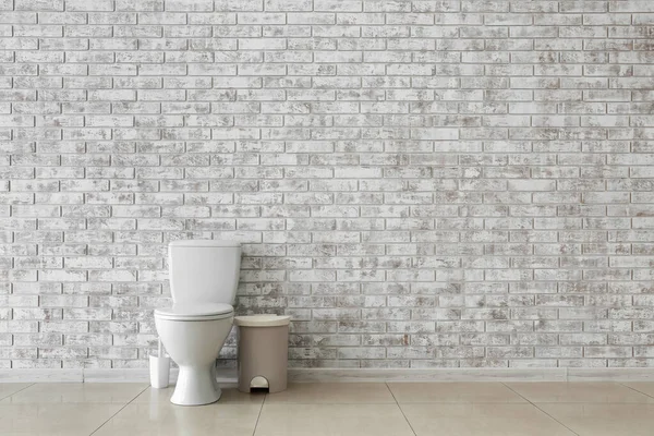 Toilet bowl near light brick wall — Stock Photo, Image