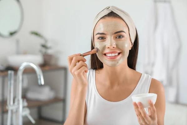 Mooie jonge vrouw die gezichtsmasker thuis toepast — Stockfoto