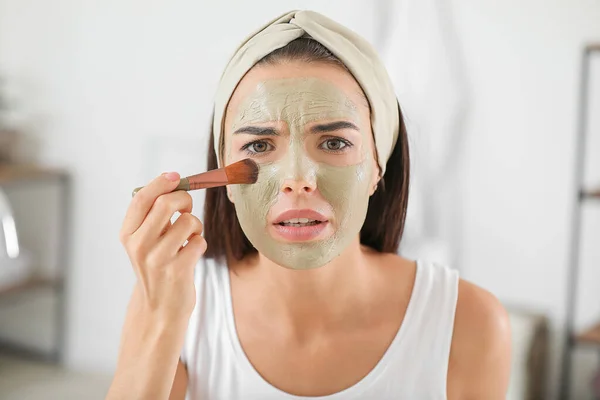 Mooie jonge vrouw die gezichtsmasker thuis toepast — Stockfoto