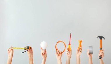 Female hands with electrician's tools on light background
