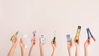 Renkli arka planda elektrikçi aletleri olan kadın eller