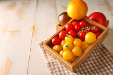 Tahta masada taze domateslerle dolu bir kutu.