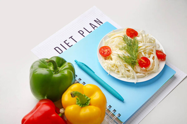 Ноутбук с диетой и здоровыми овощами на белом фоне
