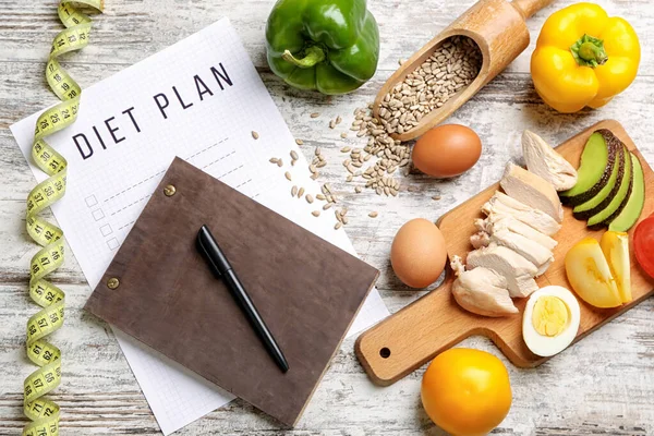 Blatt Papier mit Ernährungsplan, Maßband und gesunden Produkten auf weißem Holzgrund — Stockfoto