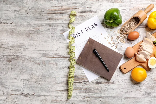 Blatt Papier mit Ernährungsplan, Maßband und gesunden Produkten auf weißem Holzgrund — Stockfoto