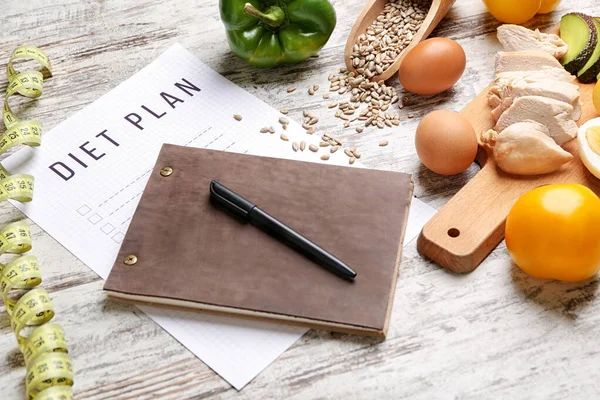 Blatt Papier mit Ernährungsplan, Maßband und gesunden Produkten auf weißem Holzgrund — Stockfoto