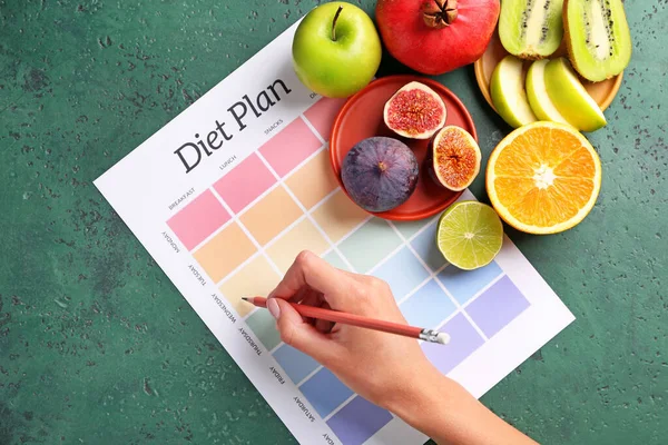 Vrouw schrijft iets op papier met dieetplan, bovenaanzicht — Stockfoto