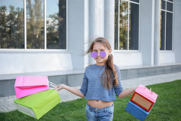 Portrait of cute fashionable girl with shopping bags outdoors — Stock fotografie