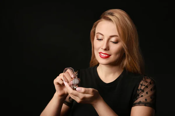 Vacker ung kvinna tillämpa makeup mot mörk bakgrund — Stockfoto