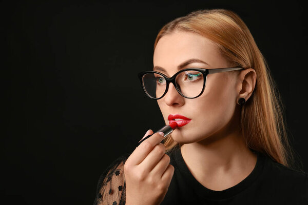 Красивая молодая женщина с помадой на темном фоне