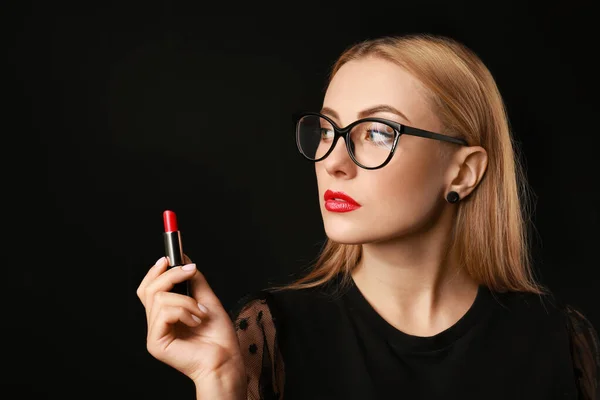 Beautiful young woman with lipstick on dark background — Stock Photo, Image