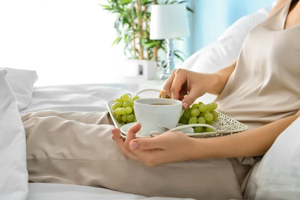 Jeune femme ayant savoureux petit déjeuner au lit — Photo