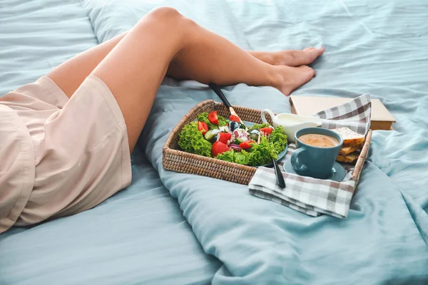 Jeune femme ayant savoureux petit déjeuner au lit — Photo