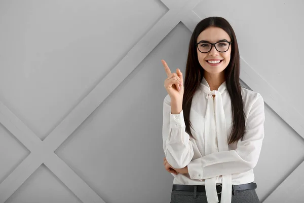 Beautiful young businesswoman with raised index finger on light background — Stock Fotó