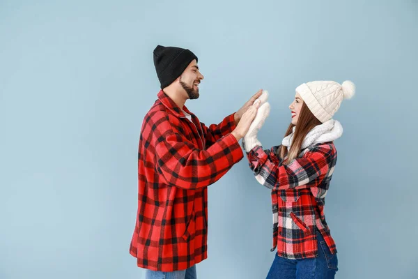 Happy young couple in warm winter clothes on color background — Stock Photo, Image