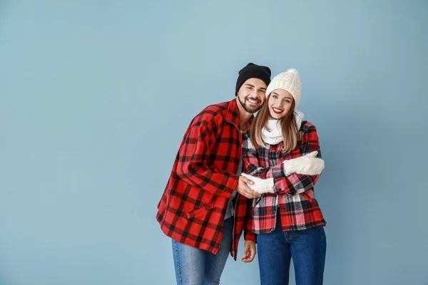 Happy young couple in warm winter clothes on color background — Stock Photo, Image