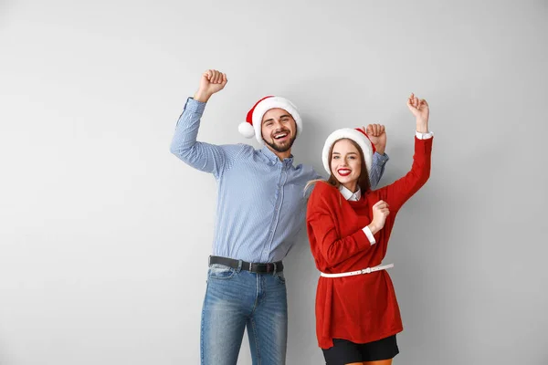 Feliz pareja joven en los sombreros de Santa sobre fondo claro — Foto de Stock