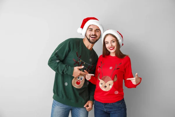 Happy young couple in Christmas clothes on light background — Stockfoto