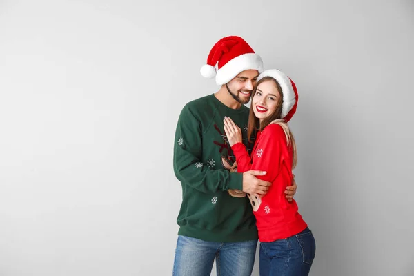 Feliz jovem casal em roupas de Natal no fundo de luz — Fotografia de Stock