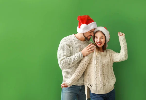 Happy young couple in Santa hats on color background — Stock Photo, Image