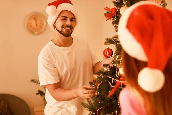 Happy young couple decorating Christmas tree at home — Stock Photo, Image