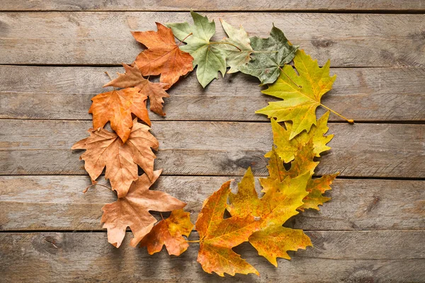 Marco hecho de hermosas hojas de otoño sobre fondo de madera — Foto de Stock