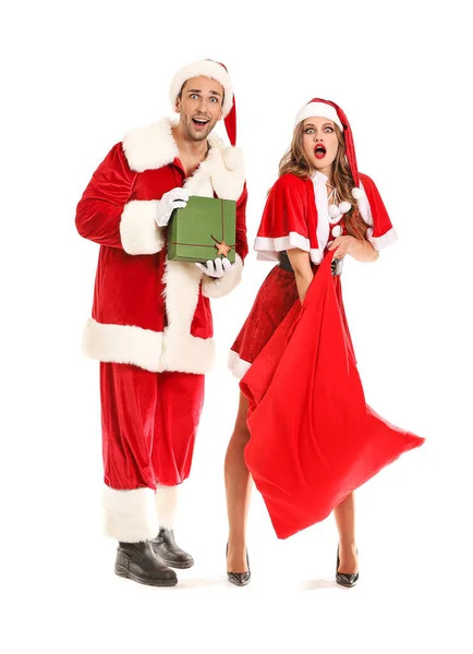 Zaskoczona młoda para przebrana za Świętego Mikołaja z prezentami świątecznymi na białym tle — Zdjęcie stockowe
