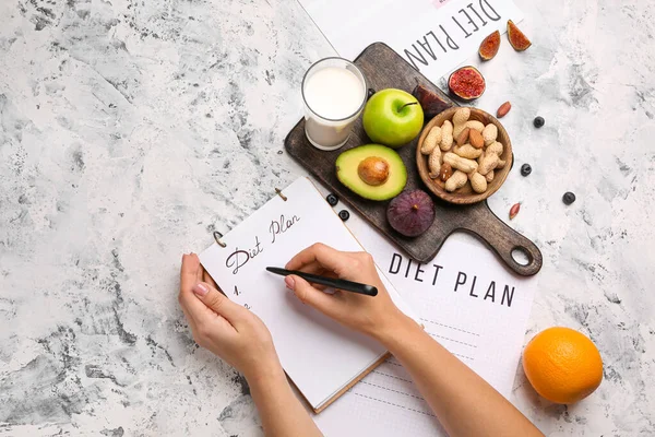 Woman writing something in notebook and healthy products on white table. Diet concept — Stock Image Woman writing something in notebook and healthy products on white table. Diet concept Stock Photo