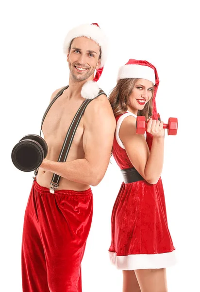 Young couple dressed as Santa Claus with dumbbells on white background — ストック写真
